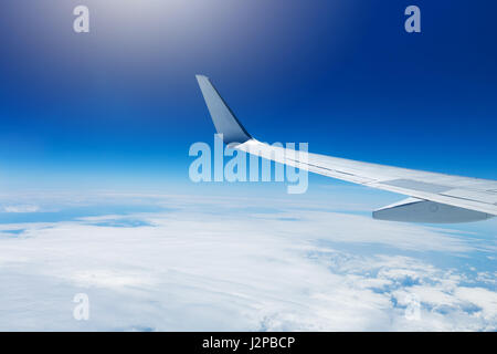 Flügel eines Flugzeugs fliegen hoch in den Himmel über den Wolken Stockfoto