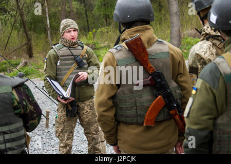 Ein Student am Yavoriv Combat Training Center OCT Academy beschriftet Peers vor einer situativen Übung, die von ukrainischen und US-Soldaten der Joint Multinational Training Group beobachtet und gecoacht wird, um die Fähigkeiten und Professionalität des CTC zu verbessern. Stockfoto