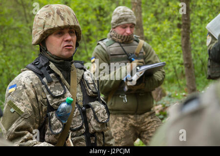 Yavoriv Combat Training Center Beobachter Controller Trainer Academy Student Slips Mitschülern einen Schlachtplan, während ein anderer OCT Akademie Student beobachtet und seine Leistung während einer Übung am 20. April Yavoriv CTC International Peacekeeping und Security Center in der Nähe von Yavoriv Ukraine bewertet.   Die OCT-Academy-Schüler wechselten als Auszubildende und ÜLG, die Ausbildung zu beobachten. Und wirkt, gleichzeitig als ÜLG waren die Schüler betreut und erzielte durch ukrainische und US-Soldaten, Joint Multinational Training Group - Ukraine zugewiesen. (Foto: Sgt. Anthony Jones, 45. Infanterie-Bri Stockfoto