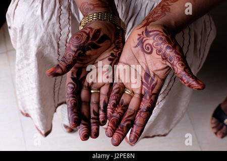 Ein kompliziertes Henna-Design auf den Handflächen und Fingern einer Frau auf der Insel Sansibar in Ostafrika. Die Designs können symbolische Bedeutungen haben, wobei verschiedene Muster Dinge wie Schönheit, Glück, Schutz oder Fruchtbarkeit darstellen. Die Dunkelheit des Henna-Flecks wird auch in einigen Kulturen als bedeutend angesehen, wobei ein dunklerer Fleck eine tiefere Liebe zwischen zwei Menschen in einer Ehe symbolisiert. Stockfoto