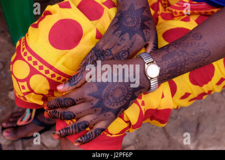 Ein kompliziertes Henna-Design auf dem Rücken und den Fingern einer Frau im Dorf Mwamgongo, das am Ufer des Tanganjika-Sees im westlichen Zentral-Tansania in Ostafrika liegt. Die Designs können symbolische Bedeutungen haben, wobei verschiedene Muster Dinge wie Schönheit, Glück, Schutz oder Fruchtbarkeit darstellen. Die Dunkelheit des Henna-Flecks wird auch in einigen Kulturen als bedeutend angesehen, wobei ein dunklerer Fleck eine tiefere Liebe zwischen zwei Menschen in einer Ehe symbolisiert. Stockfoto