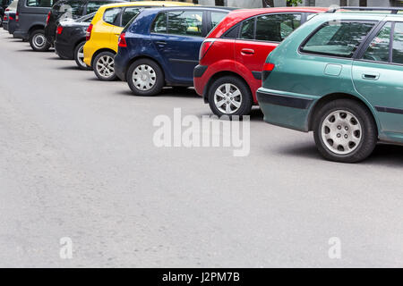 verschiedene bunte Autos geparkt diagonal am Parkplatz auf der Straße Stockfoto