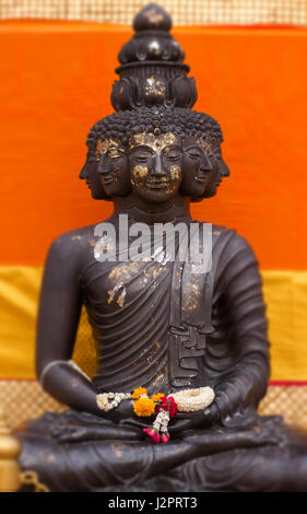 Nahaufnahme von meditieren Buddha-Statue mit Multi-Gesichter in Soft-Fokus in die orangefarbenen Hintergrund - Thailand - Bangkok - goldenen Bergs Stockfoto