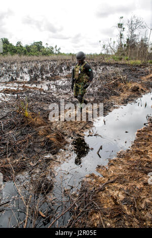 Ein Soldat Spaziergänge auf einem Deich den Transport von Öl aus der Veredler zu Lagerflächen in der Nähe einer illegalen Raffinerie während einer Patrouille in der Nähe von Warri, Delta State, Nigeria Stockfoto