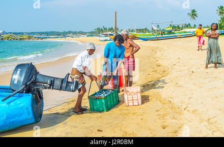 HIKKADUWA, SRI LANKA - 4. Dezember 2016: Zwei Fischer ziehen die schwere Kiste mit Fischen zu wiegen, am 4. Dezember in Hikkaduwa. Stockfoto