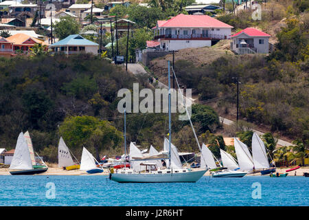 Regatta-Ansicht – Segelboote am Strand von Saline Bay mit Dorfhäuser, Saline Bay Mayreau, Saint Vincent und die Grenadinen. Stockfoto