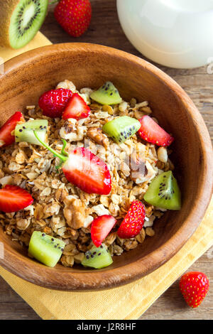Hausgemachtem Müsli mit Früchten (Erdbeere und Kiwi) in Holzschale für gesundes Frühstück hautnah Stockfoto
