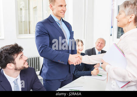 Senior Geschäftsfrau Anteil Handshake mit Auszubildenden als Zeichen der herzlichen Glückwunsch Stockfoto