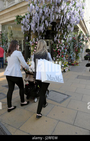 Kunstblumen mit Glyzinien grüßen Shopper am Eingang der Fenwick Kaufhaus am Brook Street und New Bond Street, London UK KATHY DEWITT Stockfoto