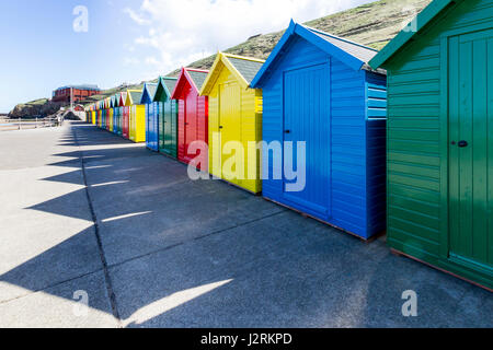 Reihe von bunten hölzernen Strandhütten entlang der Promenade West Cliff bei Whitby, North Yorkshire, England, UK Stockfoto