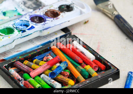 Pastelltöne für Zeichnung und Färbung. Bunte Pastellfarben ruhen in einem Fach neben eine Farbwanne mit Acrylfarben während ein Kinder-Kunst-Lektion. Stockfoto