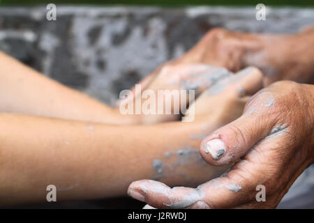 Keramik macht, Lehre Keramik.  Ältere Frau Hände Schröpfen eines kleinen Kindes Hände um Ton, wie sie gemeinsam Töpfern. Stockfoto