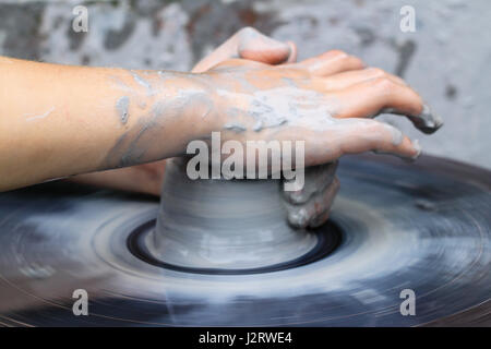 Keramik macht, Lehre Keramik.  Ein Klumpen von nassen Lehm beginnt, eine Säule zu bilden, da es ein kleines Kind auf einer Töpferscheibe formt. Stockfoto