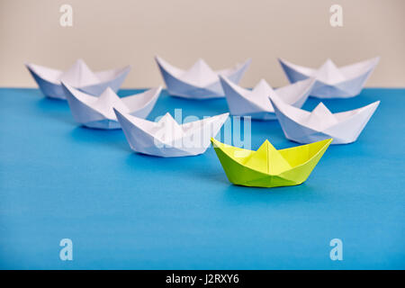 Leuchtend gelbe Papier Schiff führenden weissen basierend auf blau gegen hellen Hintergrund. Handmade und Origami. Reise um die Welt. Reise- und transporta Stockfoto