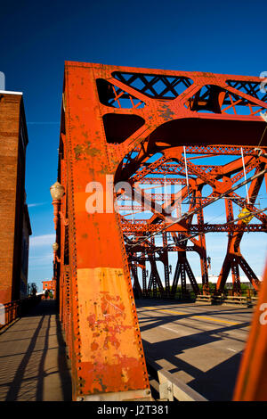 Spektakuläre kraftvolles Design genietet roten Metallbrücke in Zukunft gegen den strahlend blauen Himmel mit einem Fußweg entlang der Straße und Straßenbahn Schiene Betten Stockfoto