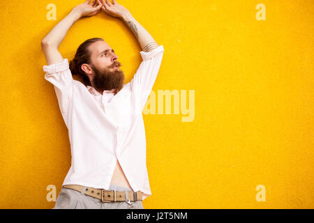 Tätowierte bärtiger Mann auf gelbe Wand Stockfoto