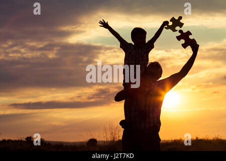 Vater und Sohn spielen im Park bei Sonnenuntergang. Leute, die Spaß auf dem Feld. Konzept für das Kind ist bereit, zur Schule zu gehen. Stockfoto