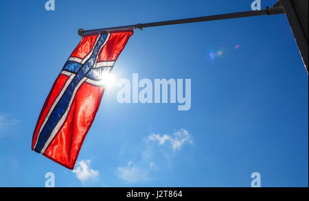 Norwegische Flagge aus nächster Nähe, in Richtung der Sonne am schönen blauen Himmel Stockfoto