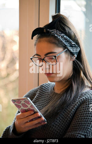 Vertikale Porträt eines jungen Mädchens mit ihr Telefon, um mit Freunden in sozialen Netzwerken zu fangen. Stockfoto