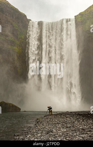 Männlichen Fotografen am unteren Rand Skogafoss Wasserfall, fotografieren, Nebel, Wasserfälle Islands. Stockfoto