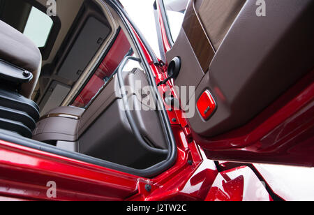 Das Innere eines modernen Luxus rot Sattelschlepper in Schattierungen von Braun Kunststoff hergestellt. Durch die offene Tür mit Holzvertäfelung LKW sichtbare Teil des Sitzes Stockfoto