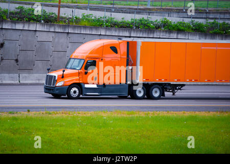 Moderne Langstrecken kommerzielle Fracht pro macht hell orange big Rig Semi LKW mit Anhänger und aerodynamische zur Kraftstoffeinsparung bei breiten multilines Staight Stockfoto