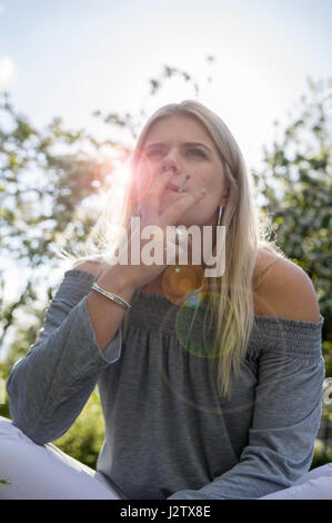 Eine junges Mädchen genießt eine Zigarette in der Sommersonne Stockfoto