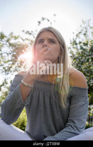 Eine junges Mädchen genießt eine Zigarette in der Sommersonne Stockfoto