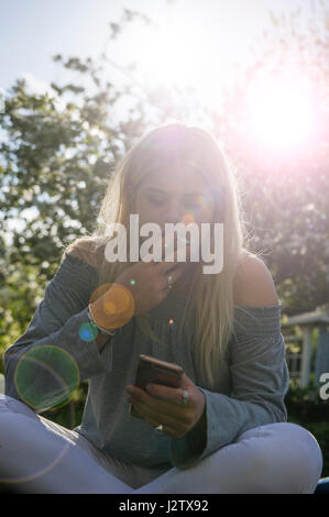 Eine junges Mädchen genießt eine Zigarette in der Sommersonne Stockfoto