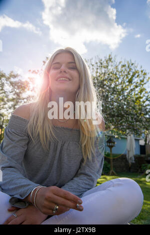 Eine junges Mädchen genießt eine Zigarette in der Sommersonne Stockfoto