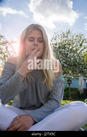 Eine junges Mädchen genießt eine Zigarette in der Sommersonne Stockfoto