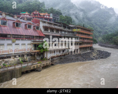 Wulai, Taiwan - 9. Oktober 2016: Landschaft von Gebäuden auf einem nebligen, regnerischen und üppigen Hügel an einem Fluss in Wulai Stockfoto