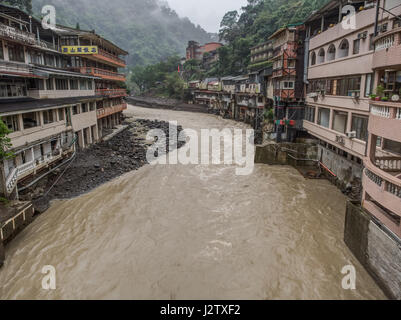 Wulai, Taiwan - 9. Oktober 2016: Landschaft von Gebäuden auf einem nebligen, regnerischen und üppigen Hügel an einem Fluss in Wulai Stockfoto