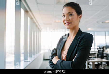 Porträt von Reife Geschäftsfrau mit ihren verschränkten Armen im Büro stehen und Lächeln auf den Lippen. Asiatische weibliche Führungskraft Blick in die Kamera sicher. Stockfoto