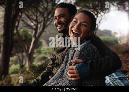 Junge Asiatin mit ihrem Freund im Freien sitzen und Lächeln auf den Lippen. Junge Wanderer-paar nach Wanderung ausruhen. Stockfoto