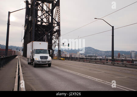 Semi-LKW der Mittelklasse-Tragfähigkeit weiße Box mit einem Stand auf der Straße durch das alte Eisen Aufzug Fachwerkbrücke über den Willamette river Stockfoto