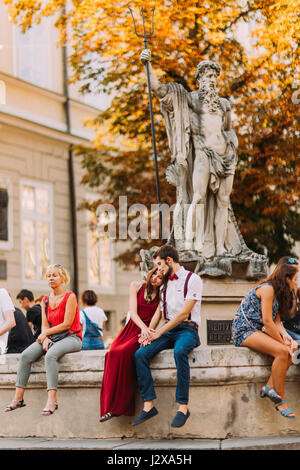 Zärtlich junges Paar sitzt auf dem alten Vintage Brunnen in Lviv Stadtzentrum Stockfoto