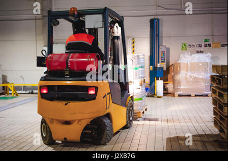 Lagermitarbeiter im Overall Kleidung, Fahrer Ausstellungsgeräte fleißig an Logistik Moving on Loader Paletten mit Bierfässer auf Linie der Fabrik für Pro Stockfoto