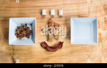 Hundefutter in einem rechteckigen schwarzen Teller über einem Holzbrett serviert sehr chic Weise. Stockfoto