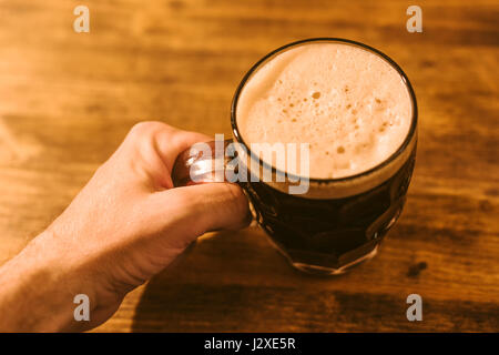 Menschen trinken dunkles Bier im britischen Grübchen Glaskrug Bier am Stehtisch Stockfoto