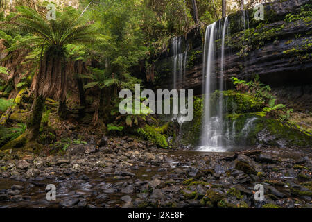 Langzeitbelichtung eines Wasserfalls mit einem seidigen Look, umgeben von üppiger Vegetation und Felsen mit Moos bedeckt. Stockfoto