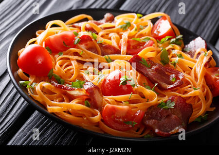 Leckere Möhren Nudeln mit gebratenem Speck, grünen und frischen Tomaten Nahaufnahme auf einem Teller auf den Tisch. horizontale Stockfoto