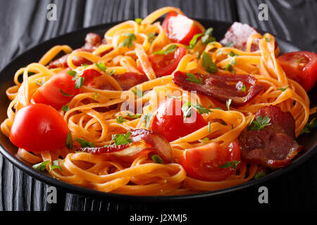 Karotten-Nudeln mit Speck und Tomaten Nahaufnahme auf einer Platte. horizontale Stockfoto