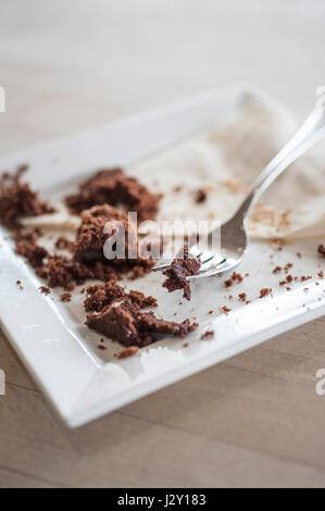 Speisereste ein Schokoladenkuchen Krümel Teller Gabel gegessen genossen behandeln zufrieden Stockfoto