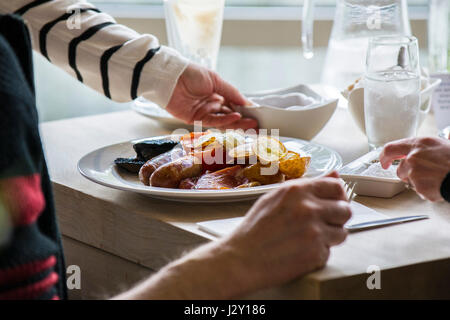 Ein englisches Frühstück braten bis zu einem Kunden in einem Restaurant serviert. Stockfoto