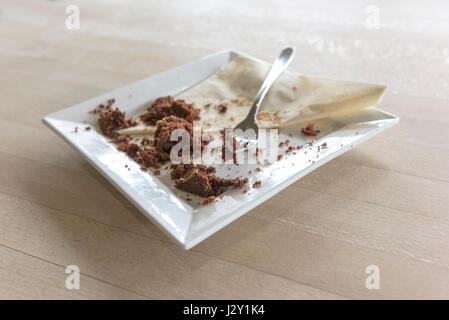 Speisereste ein Schokoladenkuchen Krümel Teller Gabel Besteck Serviette Serviette gegessen verbraucht zufrieden Zufriedenheit behandeln Genuss Stockfoto