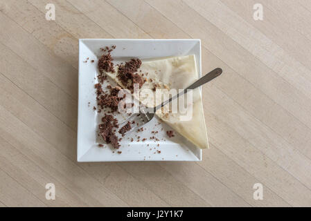 Speisereste ein Schokoladenkuchen Krümel Teller Gabel Besteck Serviette Serviette gegessen verbraucht zufrieden Zufriedenheit behandeln Genuss Stockfoto