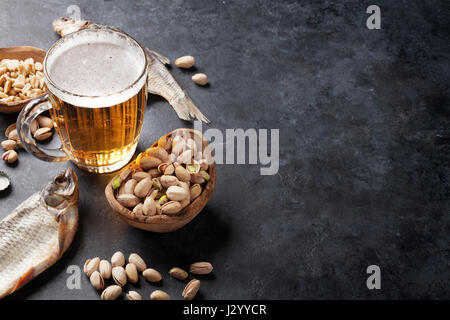 Lager-Bier und Snacks am Steintisch. Muttern, gesalzener Fisch. Mit Textfreiraum Stockfoto