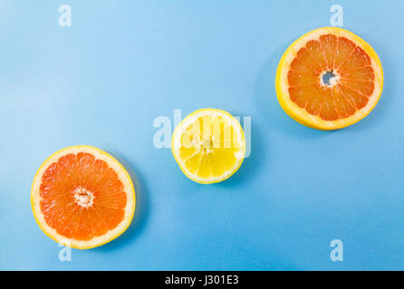 Eine Grapefruit und zwei Zitronenscheiben auf blauem Hintergrund. Minimalistische Bildstil mit textfreiraum für text Stockfoto