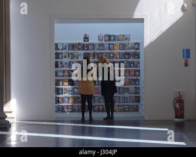 Zwei Mädchen, die Auswahl von DVDs in Glasgow GOMA Stockfoto